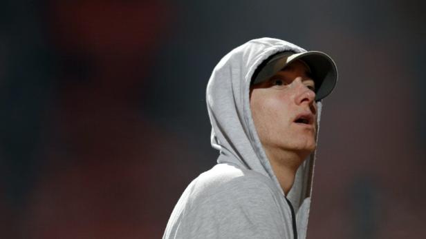 Eminem mit Kapuzenpullover und Baseballkappe blickt nach oben.