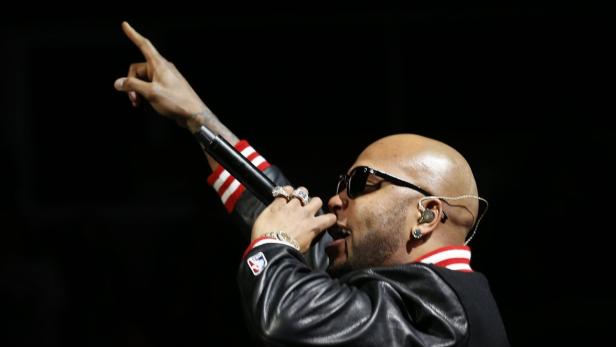 Ein Rapper mit Sonnenbrille und Mikrofon tritt auf einer Bühne auf.