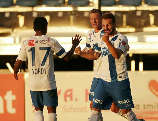 Zwei Fußballspieler jubeln, während ein dritter Spieler mit der Nummer 17 sich ihnen zuwendet.