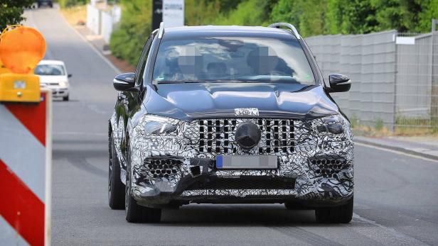 Ein getarntes Mercedes-Benz-SUV-Modell fährt auf einer Straße.