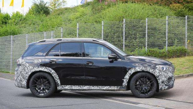 Ein schwarzer Mercedes-Benz GLE mit Tarnmuster an Front und Heck fährt auf einer Straße.