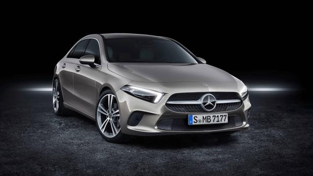 Ein grauer Mercedes-Benz steht auf einer dunklen Oberfläche.