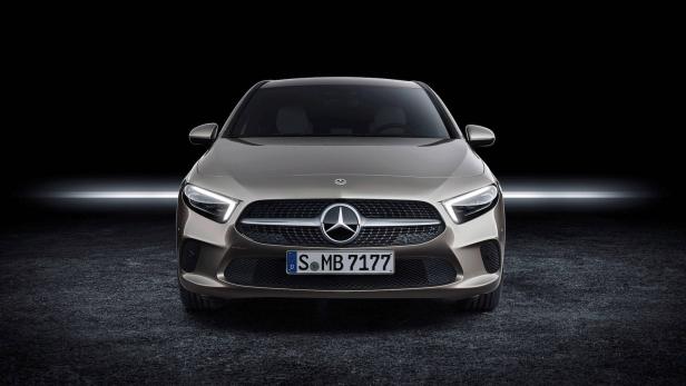 Ein grauer Mercedes-Benz steht vor einem dunklen Hintergrund.
