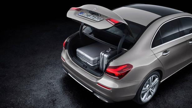 Ein grauer Mercedes mit geöffnetem Kofferraum, in dem zwei silberne Koffer stehen.