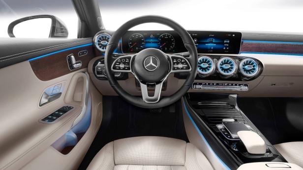 Innenraum eines Mercedes-Benz mit beigen Ledersitzen und blau beleuchteten Lüftungsdüsen.