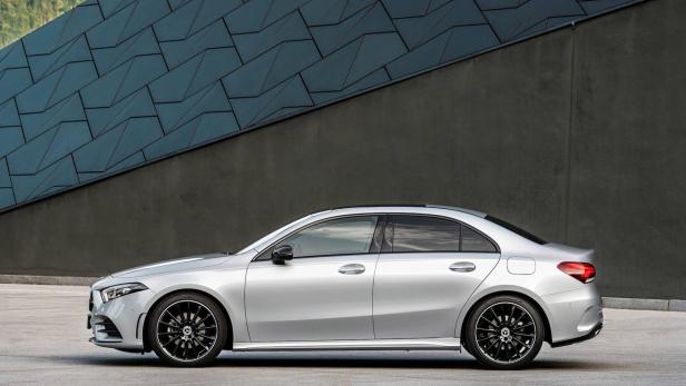 Eine silberne Mercedes-Benz A-Klasse Limousine vor einer grauen Wand.