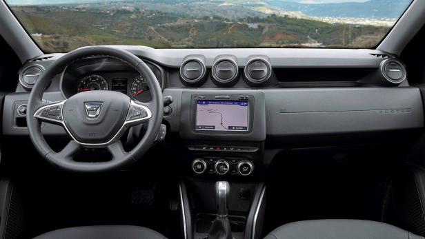 Das Interieur eines Dacia Duster mit Navigationssystem und Blick auf eine hügelige Landschaft.