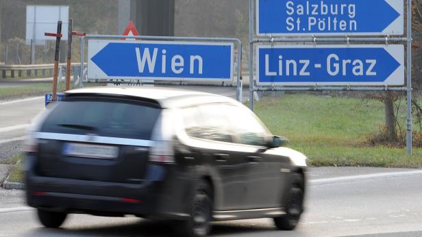 Ein Auto fährt an Wegweisern nach Wien, Linz, Graz, Salzburg und St. Pölten vorbei.