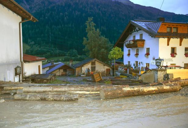 Hochwasser hat Baumstämme vor Häusern in einem Dorf abgelagert.