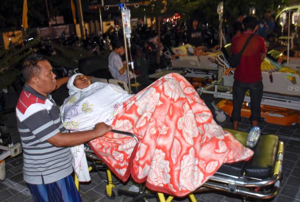 A person injured during a strong earthquake waits for treatment outside the Mataram City hospital with other patients who were evacuated, in Mataram, Lombok island