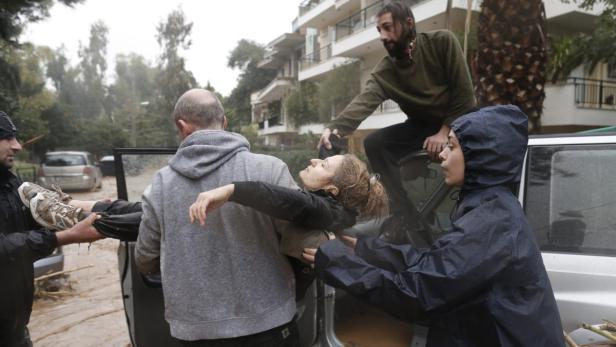 Helfer tragen eine Frau durch das Hochwasser zu einem Auto.