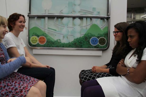 Zwei lächelnde Frauen sitzen zwei grimmig dreinblickenden Frauen gegenüber.