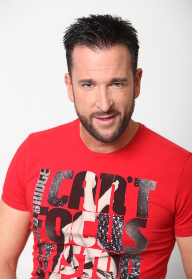 Porträt von Sänger und Fernsehmoderator Andreas Gabalier mit Bart und rotem T-Shirt.