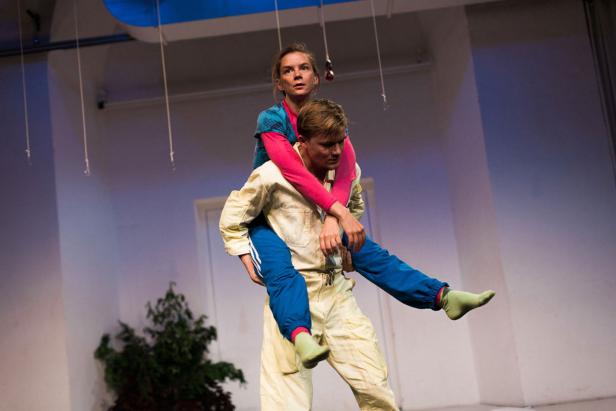 Ein Mann trägt eine Frau huckepack auf einer Bühne.