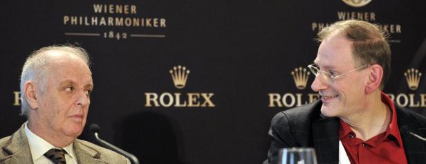 Zwei Männer sitzen vor einem Hintergrund der Wiener Philharmoniker und Rolex.