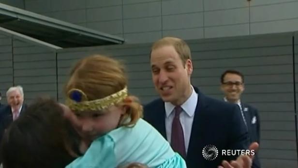 Prinz William beobachtet, wie ein kleines Mädchen umarmt wird.
