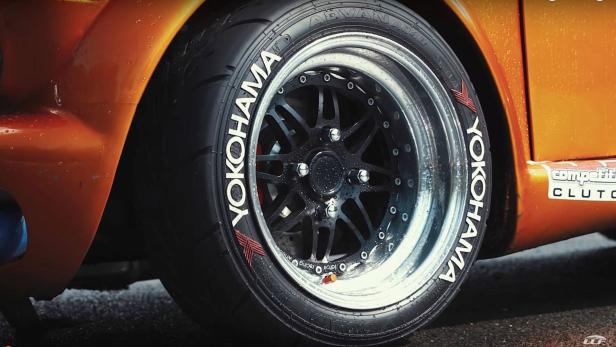 Nahaufnahme eines Yokohama-Reifens an einem orangefarbenen Auto.