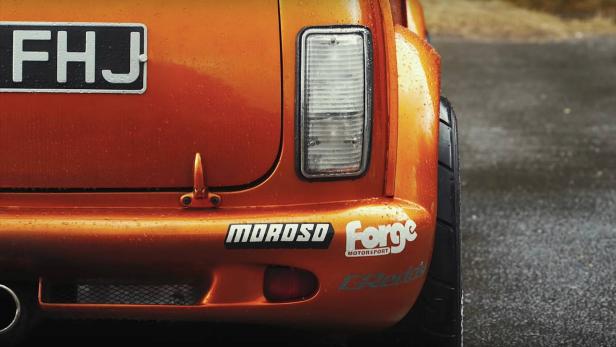Die Rückansicht eines orangefarbenen Autos mit den Aufklebern „Moroso“ und „Forge Motorsport“.
