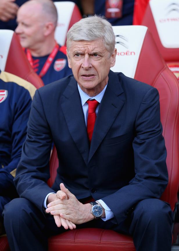 Arsène Wenger sitzt auf der Bank und schaut auf das Spielfeld.