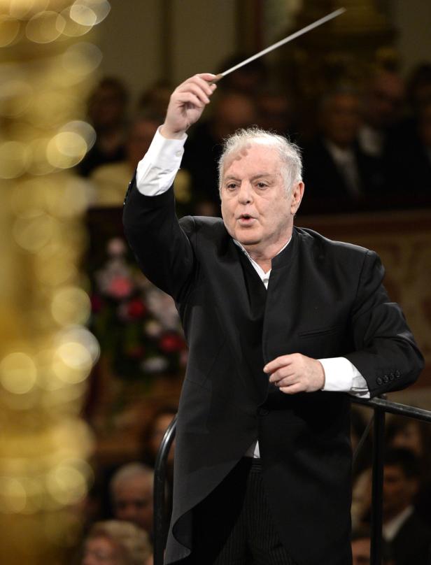 Ein Dirigent mit erhobenem Taktstock vor einem Orchester.