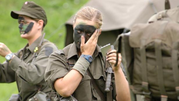 Zwei Soldatinnen mit Tarnfarbe im Gesicht während einer Übung.
