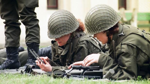 Zwei Soldatinnen liegen auf einer Wiese und inspizieren ihre Gewehre.