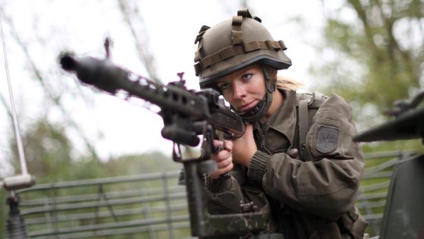 Eine Soldatin des österreichischen Bundesheeres zielt mit einem Maschinengewehr.