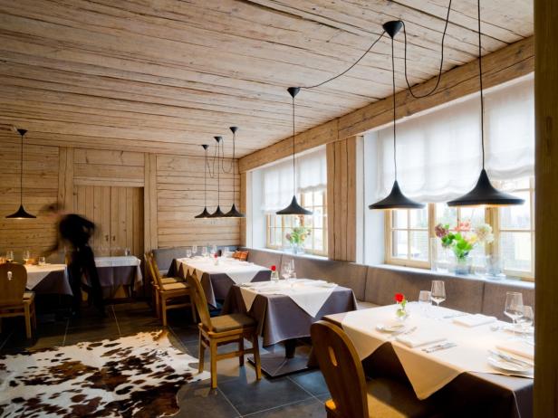 Ein Restaurant mit Holzwänden, gedeckten Tischen und modernen Hängelampen.