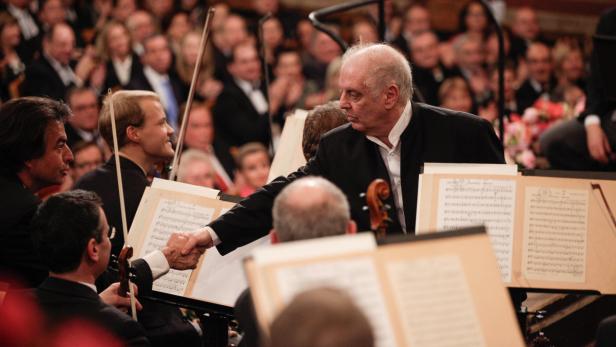 Ein Dirigent schüttelt einem Orchestermitglied die Hand vor Publikum.
