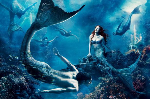 Mehrere Meerjungfrauen und Meermänner schwimmen in einem blauen Ozean mit Korallenriffen.