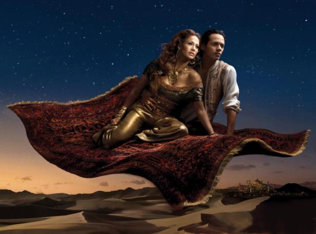 Jennifer Lopez und Marc Anthony auf einem fliegenden Teppich vor einer Wüstenlandschaft.