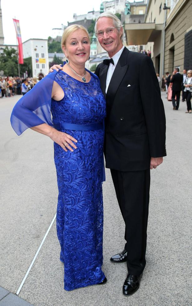Ein elegant gekleidetes Paar posiert vor einem Gebäude in Salzburg.
