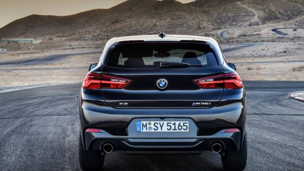 Die Rückansicht eines schwarzen BMW X2 M35i auf einer asphaltierten Straße.