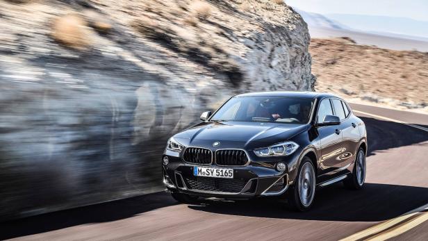 Ein schwarzer BMW X2 fährt auf einer kurvenreichen Straße.