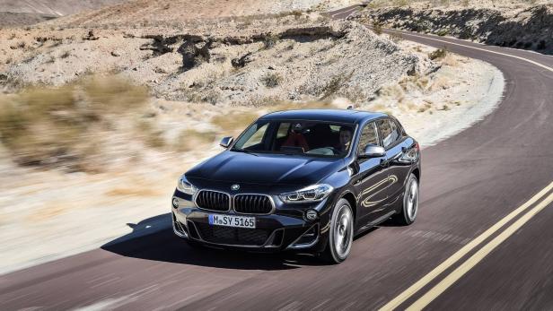 Ein schwarzer BMW X2 fährt auf einer kurvenreichen Straße durch eine Wüstenlandschaft.