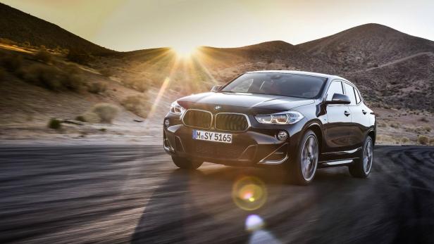 Ein schwarzer BMW X2 fährt auf einer Straße in einer Wüstenlandschaft.