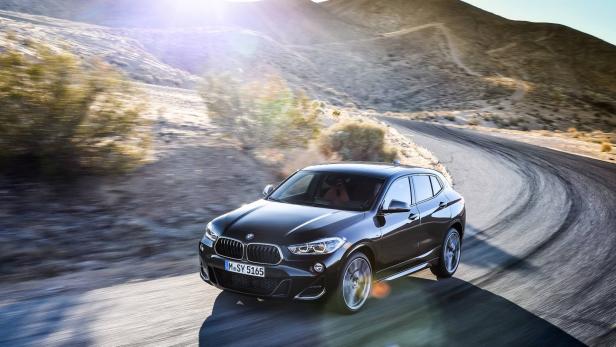 Ein schwarzer BMW X2 fährt auf einer kurvenreichen Straße durch eine Wüstenlandschaft.