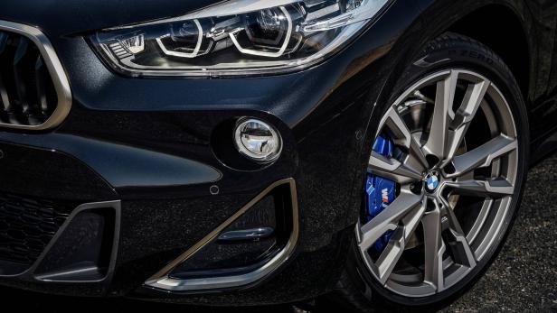 Detailansicht der Frontpartie eines schwarzen BMW mit blauen Bremssätteln.