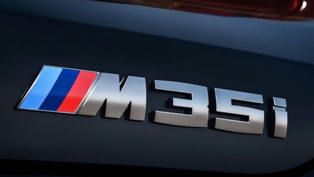 Das „M35i“-Logo eines BMW, das die typischen M-Farben trägt.
