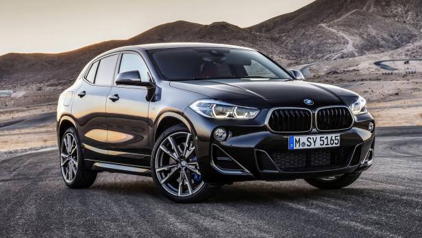 Ein schwarzer BMW X2 steht auf einer asphaltierten Straße vor einer Bergkulisse.