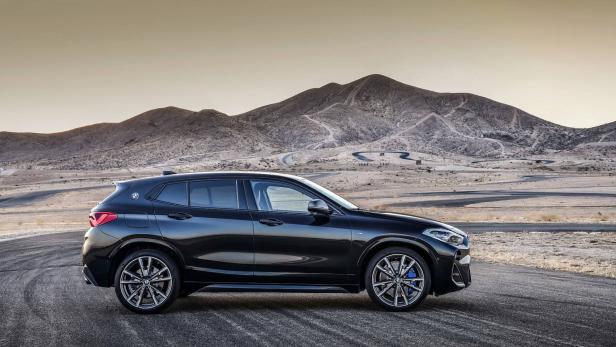 Ein schwarzer BMW X2 vor einer Wüstenlandschaft mit Bergen im Hintergrund.