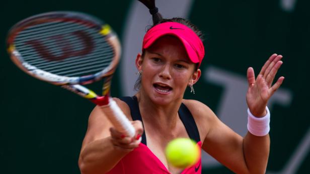 Eine Tennisspielerin schlägt einen Ball mit ihrem Schläger.