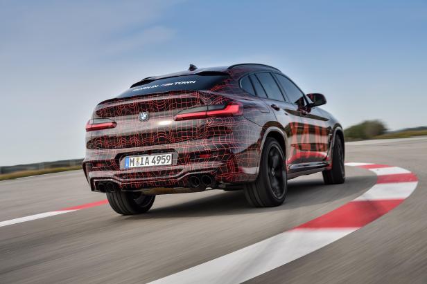 Ein BMW X4 mit auffälliger Tarnung auf einer Rennstrecke.