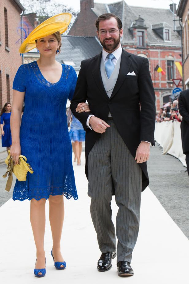 Ein Paar in formeller Kleidung geht auf einem weißen Teppich.