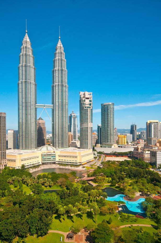 Die Petronas Towers erheben sich über einen Park mit Schwimmbad in Kuala Lumpur.