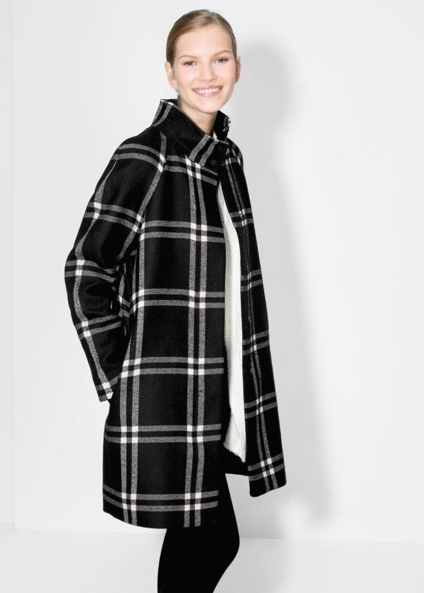 Eine Frau trägt einen schwarz-weiß karierten Mantel.