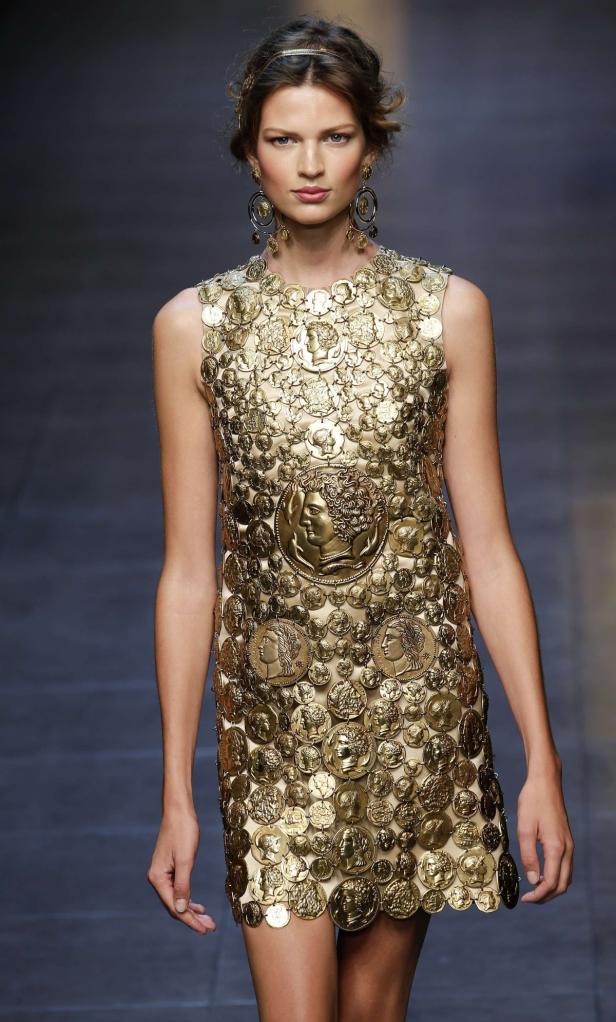 Eine Frau trägt ein goldenes Kleid, das mit Münzen verziert ist.