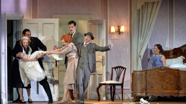 Szene aus einer Theateraufführung mit mehreren Darstellern in Kostümen auf einer Bühne.