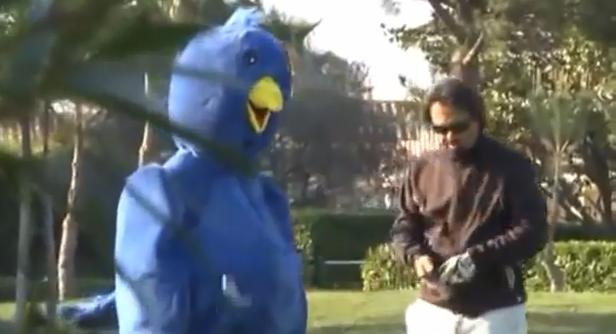 Eine Person im blauen Vogelkostüm steht neben einem Mann im Freien.