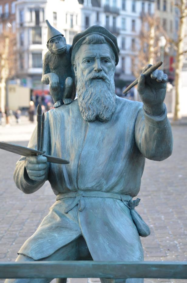 Eine Statue eines Malers mit Pinsel und Palette, auf dessen Schulter ein Affe mit Narrenkappe sitzt.
